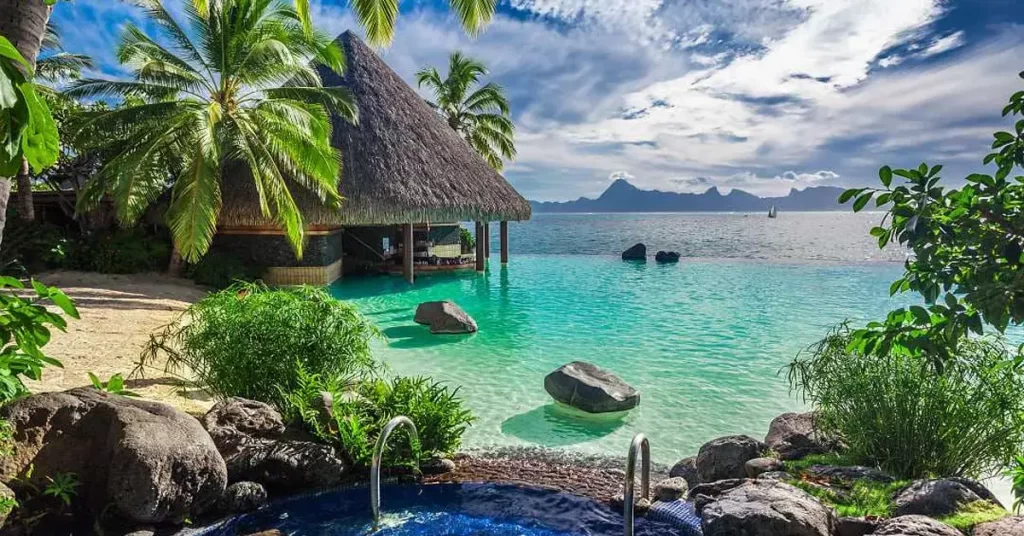 A beautiful scene from Tahiti's Beach. A bright blue sky and blue ocean show casing the beauty of Tahiti Vacations.